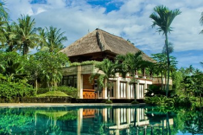 a house next to a body of water surrounded by palm trees