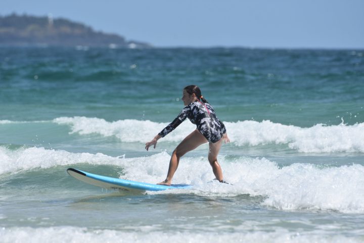 a young girl riding a wave on a surfboard in the ocean