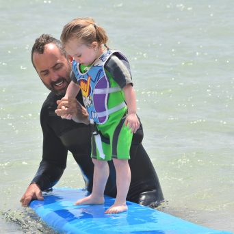a young boy standing next to a body of water