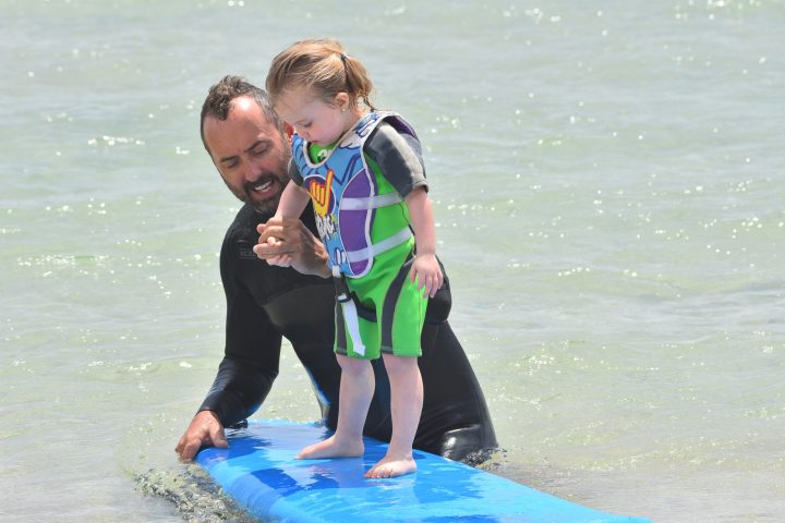 a young boy standing next to a body of water