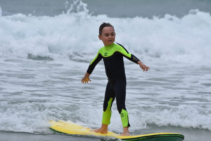 a young girl riding a wave on a surfboard in the water