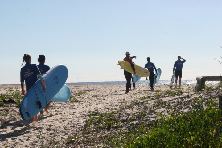 a group of people on a beach holding a surfboard
