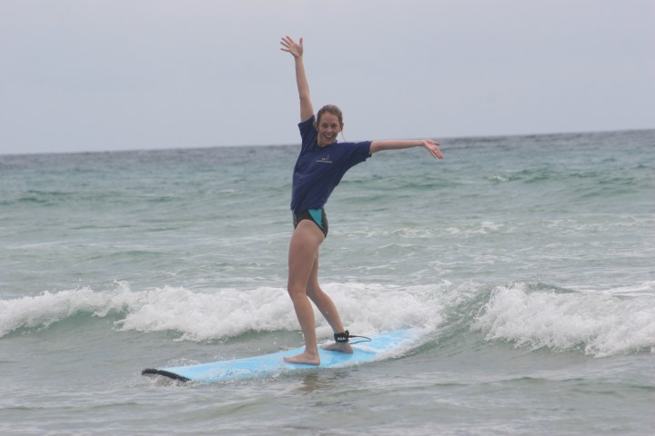 a young girl riding a wave on a surfboard in the ocean